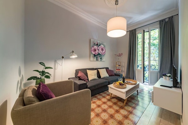 A living room with a sofa, armchair, coffee table, and a painting on the wall.