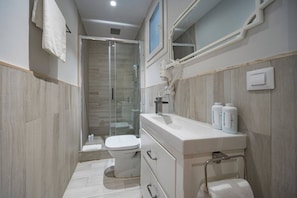 A modern bathroom with a glass-enclosed shower, a toilet, and a vanity with storage.