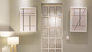 Una stanza con una porta bianca, un comodino con una lampada e due quadri astratti incorniciati appesi al muro.