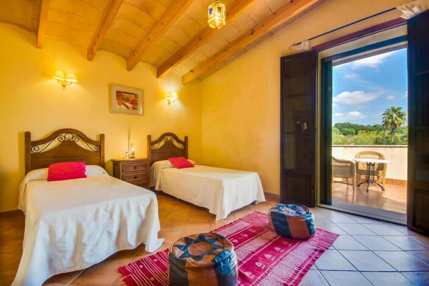 Habitació amb dos llits, una catifa vermella i vista a l'exterior.