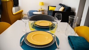 A dining table set with yellow plates, clear glasses, and a teal placemat. - Charming town house Avignon intra muros (Avignon)