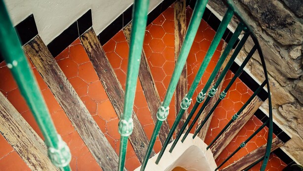 A spiral staircase with a wooden handrail and green metal balusters. - Charming town house Avignon intra muros (Avignon)