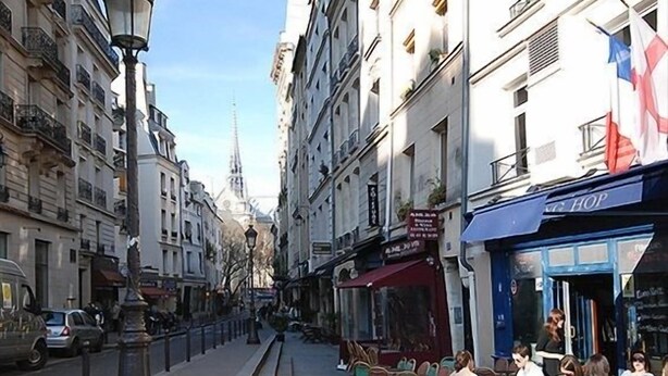 A street with outdoor seating, buildings, and a lamppost.