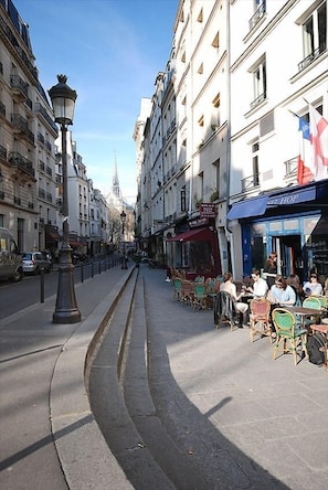 A street with outdoor seating, buildings, and a lamppost.