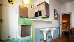 A compact kitchen with a microwave, a sink, and a small refrigerator. There is a dining area with a table and chairs.