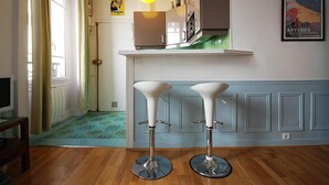 A kitchen with a white countertop, a hanging light fixture, and a poster on the wall.