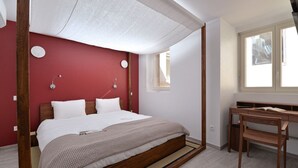 Een slaapkamer met een bed, een bureau en een raam.