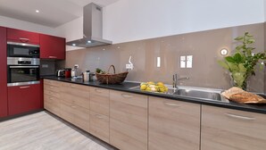 Een moderne keuken met rode kastjes, roestvrijstalen apparatuur en een zwart aanrecht.