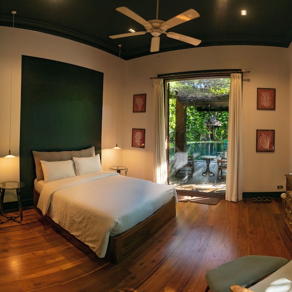 Un dormitorio con una cama grande, un ventilador de techo y vista a un patio exterior.