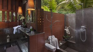 A modern bathroom with a wooden vanity, a shower with a glass enclosure, and a view of lush greenery outside. - Chandra Residence (Hang Dong)
