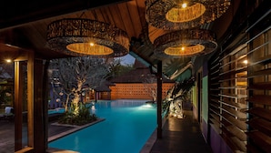 A pool area with wooden decking and hanging lamps. - Chandra Residence (Hang Dong)