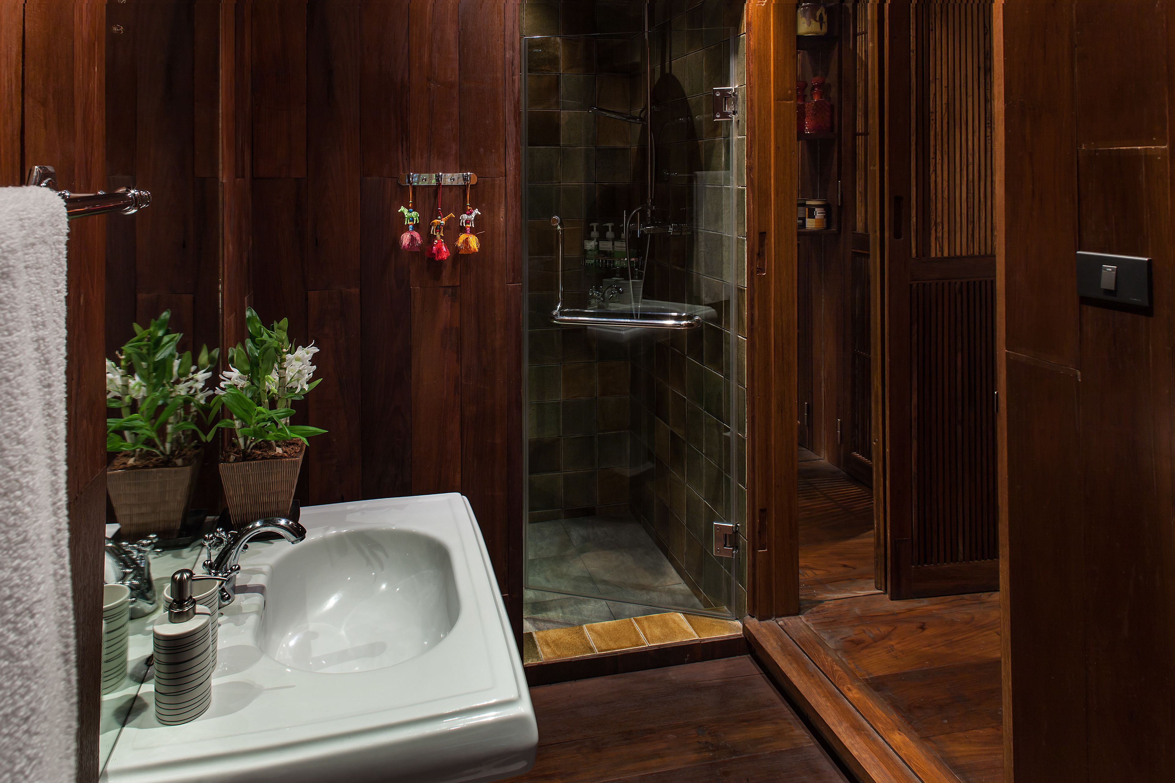 Une salle de bain avec un meuble-lavabo en bois, une douche en verre et une plante en pot.