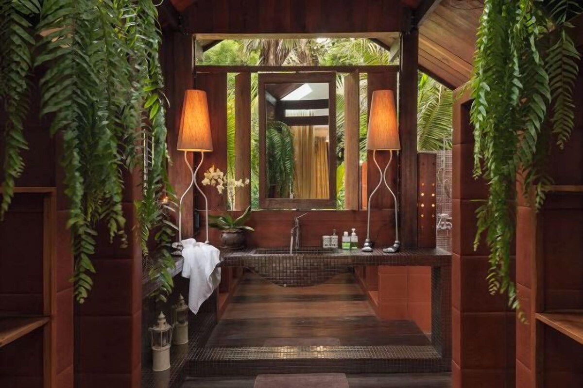 A wooden bathroom with a sink, mirror, and hanging plants.