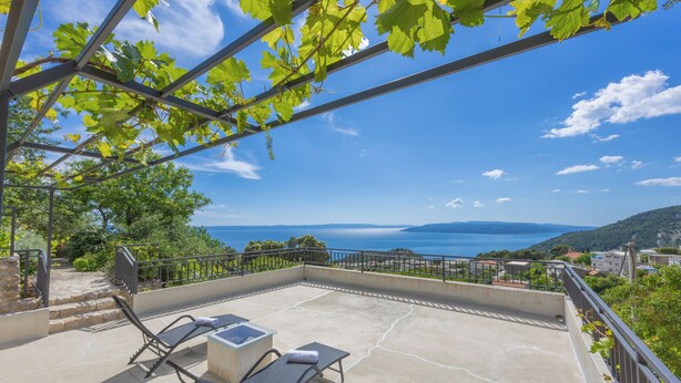 A terrace with two lounge chairs and a table, overlooking a scenic view of the sea and hills. - Detached house with sea views, on 2. 000qm plot, 2 Schlafzi. (Makarska)