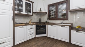 A kitchen with white cabinetry, a black oven, and a wooden countertop. - Detached house with sea views, on 2. 000qm plot, 2 Schlafzi. (Makarska)