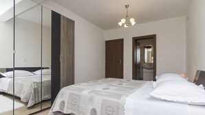 A bedroom with a large mirror, a bed with a quilt, and a ceiling light. - Detached house with sea views, on 2. 000qm plot, 2 Schlafzi. (Makarska)