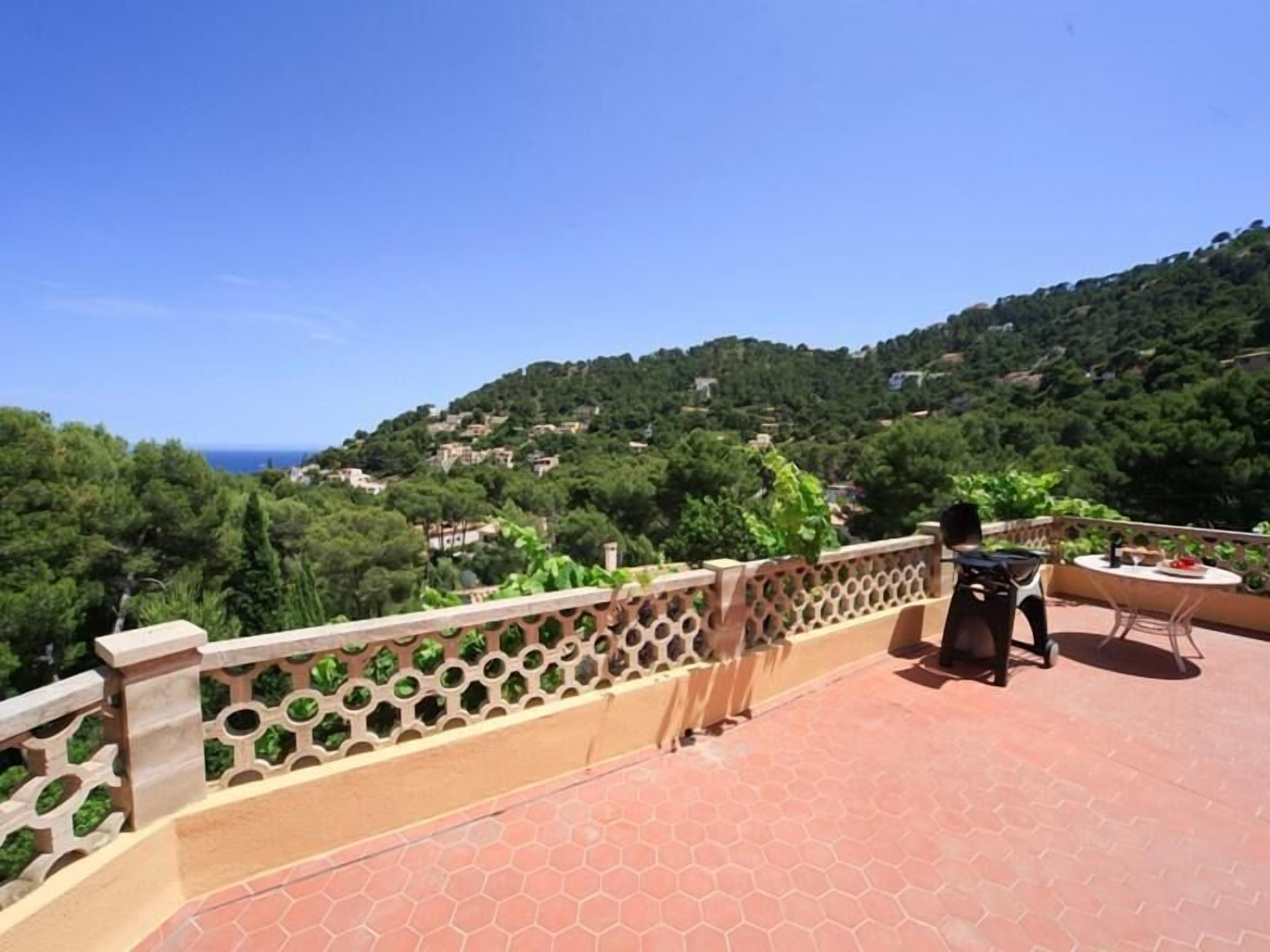 A terrace with a view of a hillside and the sea.