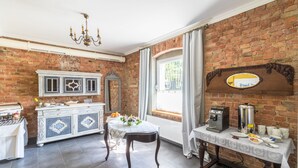 Una cocina con pared de ladrillo, encimera blanca, estufa, pileta y ventana con cortinas.