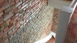 Una escalera con un muro de ladrillo a un lado y una barandilla blanca.