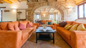 A cozy living room with orange sofas, a black coffee table, and a stone archway.