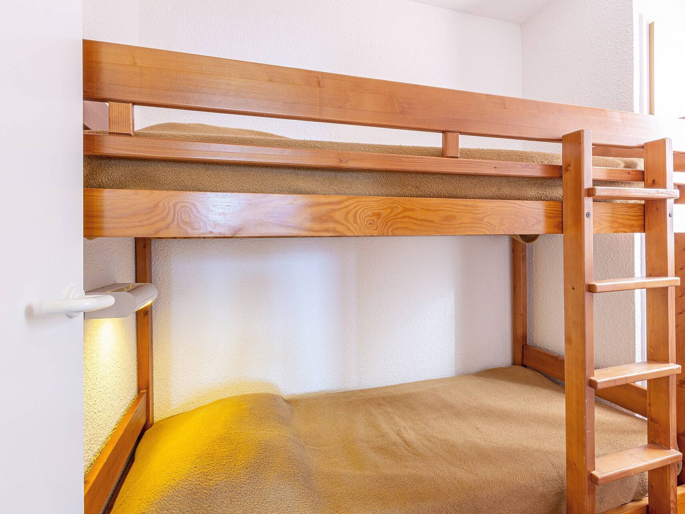 Een stapelbed met een houten trapje en een klein plankje.