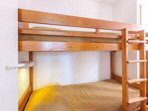 Una cama litera con una escalera de madera y un pequeño estante.