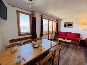 Un coin repas chaleureux avec une table en bois, des chaises et un canapé rouge.