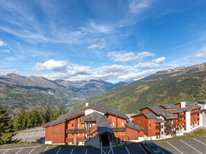 Un albergue de montaña con varias construcciones de madera, un estacionamiento y vistas de montañas nevadas.