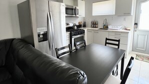 A modern kitchen with white cabinets, a black countertop, and a dining area with a black table and chairs. - Located only minutes away from the Palm Beaches. 2 bedroom 3 beds 2 bathroom (Noord)