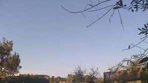 Una piscina con una vista despejada del paisaje circundante, incluyendo árboles y un edificio distante.