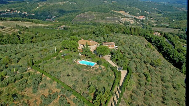 Una villa con piscina, rodeada de exuberante vegetación y colinas.