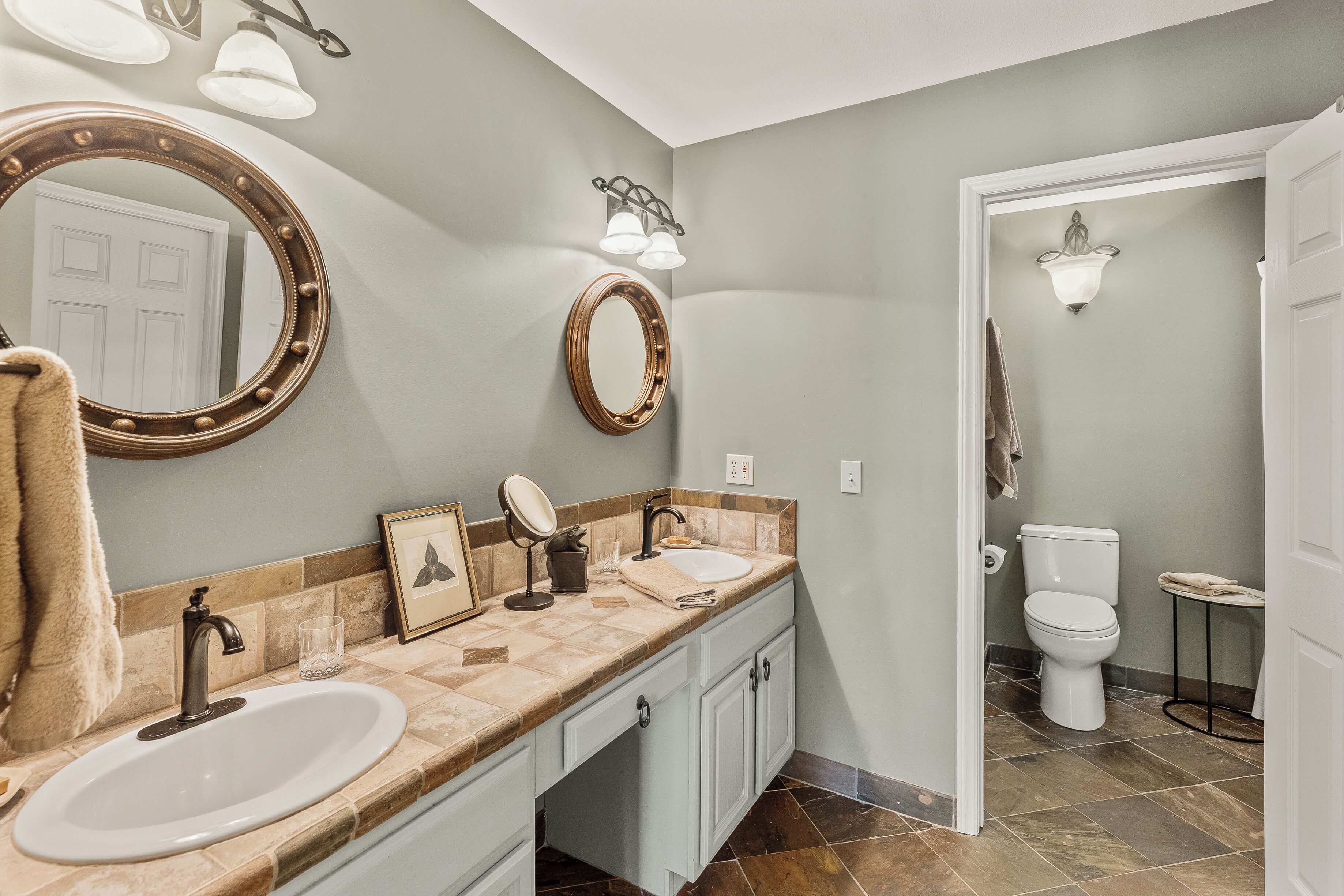 Une salle de bain comprenant un meuble-lavabo, deux miroirs, un évier et des toilettes.