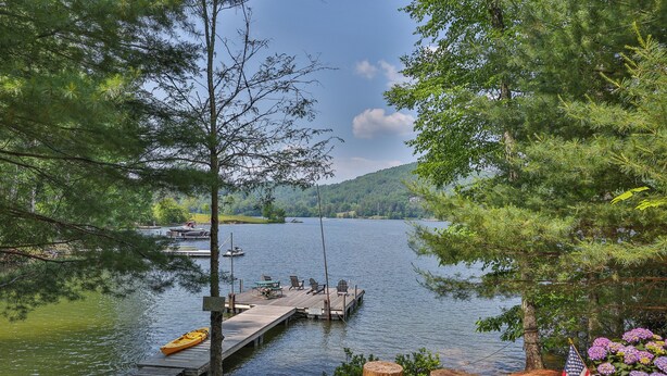 A lakeside dock with a kayak, dock chairs, and an American flag.