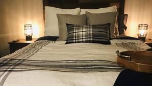 A neatly made bed with a striped bedspread, two pillows, and a headboard with a wooden panel design. There are two bedside tables with lamps on either side of the bed. - Clean Mountain Getaway! Excellent location in Mammoth w/full renovation (Mammoth Lakes)