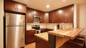 A modern kitchen with wooden cabinets, stainless steel appliances, and a wooden island. - Clean Mountain Getaway! Excellent location in Mammoth w/full renovation (Mammoth Lakes)