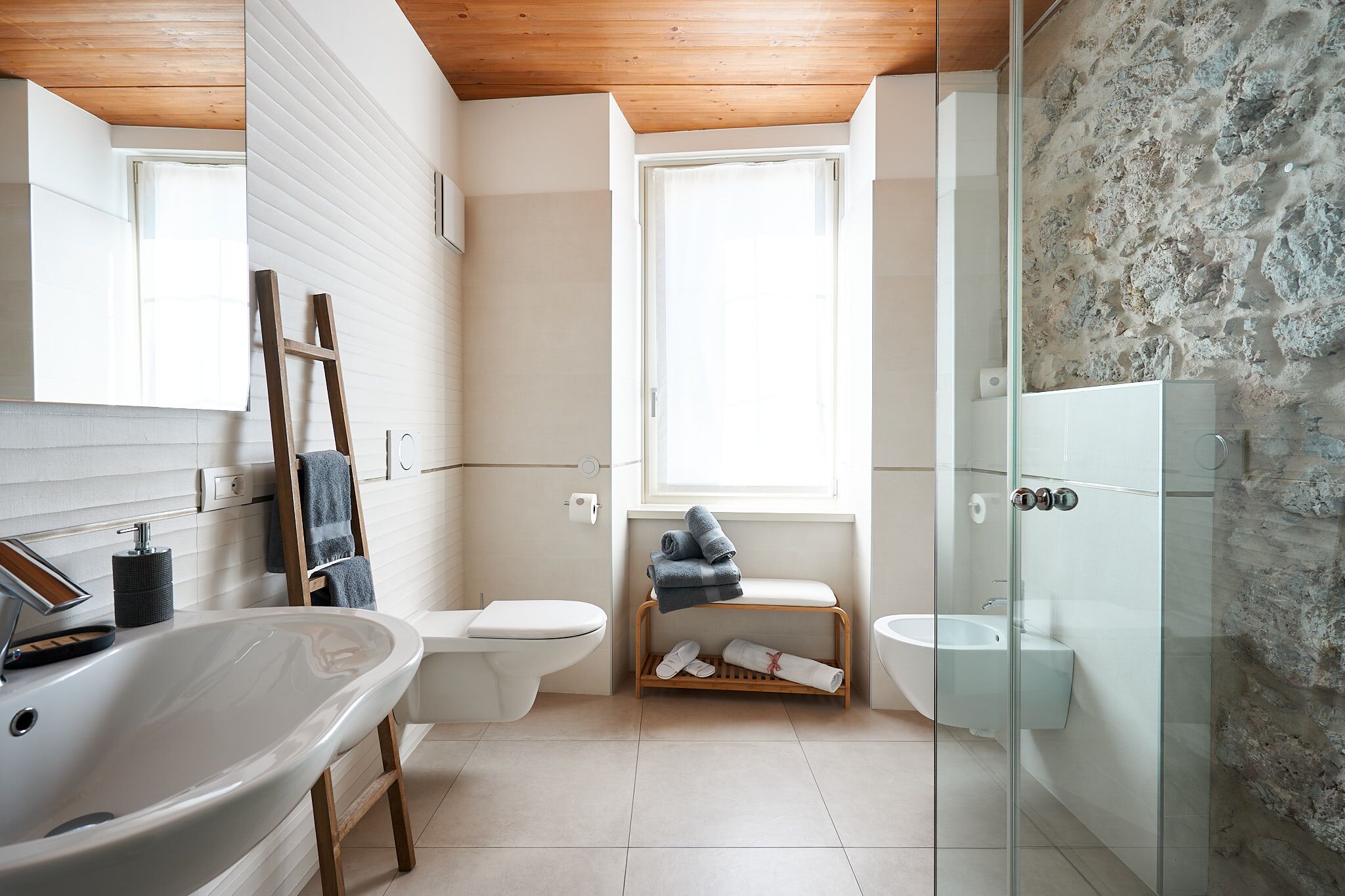 A modern bathroom with a freestanding bathtub, a glass-enclosed shower, a toilet, and a sink.
