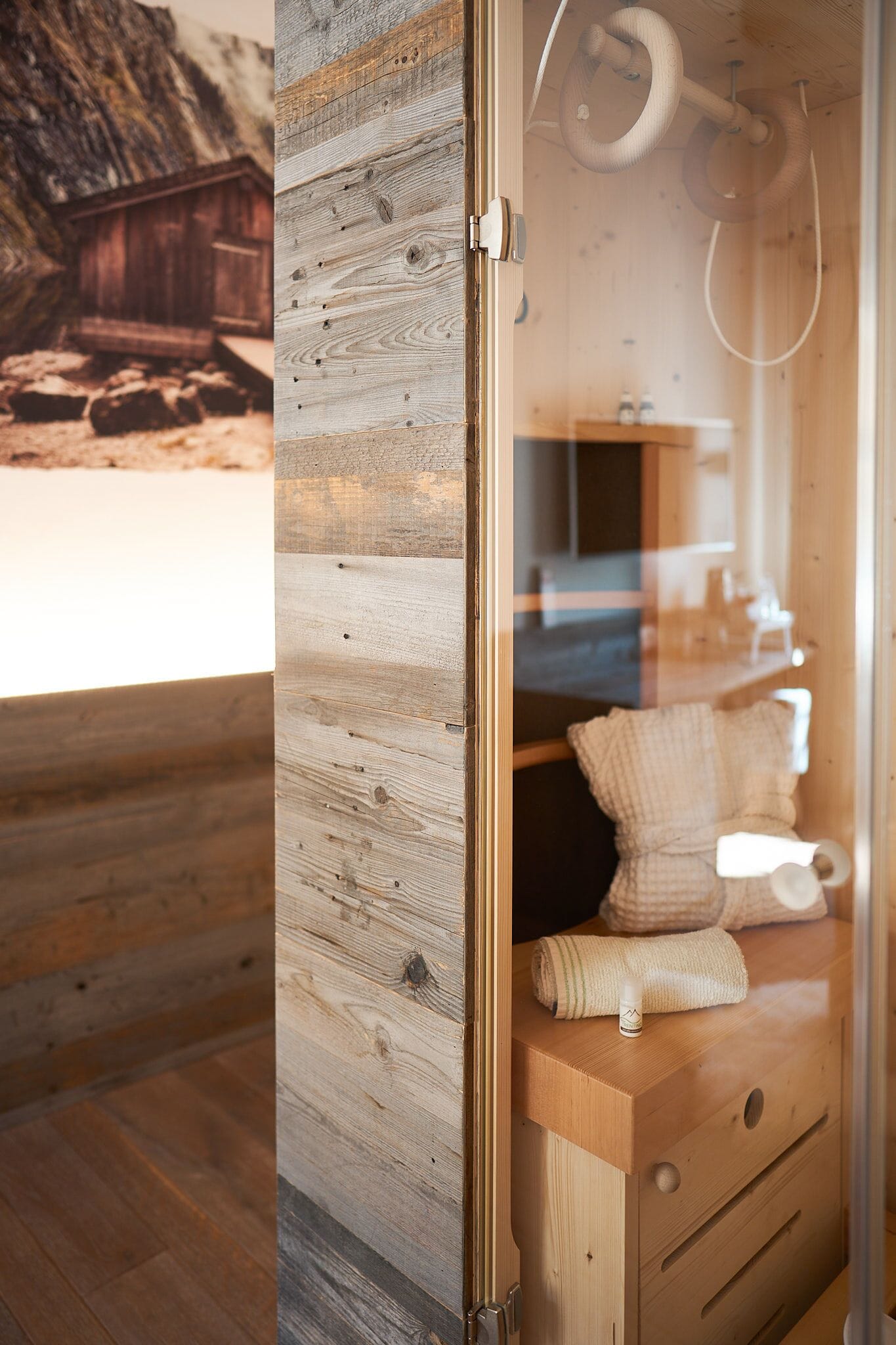 Interior de una cabaña de madera con un estilo rústico, que incluye una pared de madera, un banco de madera y una pequeña estructura de madera en el exterior.