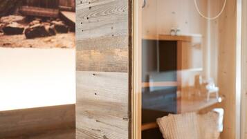 Interior de una cabaña de madera con un estilo rústico, que incluye una pared de madera, un banco de madera y una pequeña estructura de madera en el exterior.