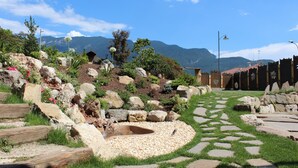 A garden with a pond, rocks, and a wooden fence. - La Filanda Relax & Gourmet (Denno)