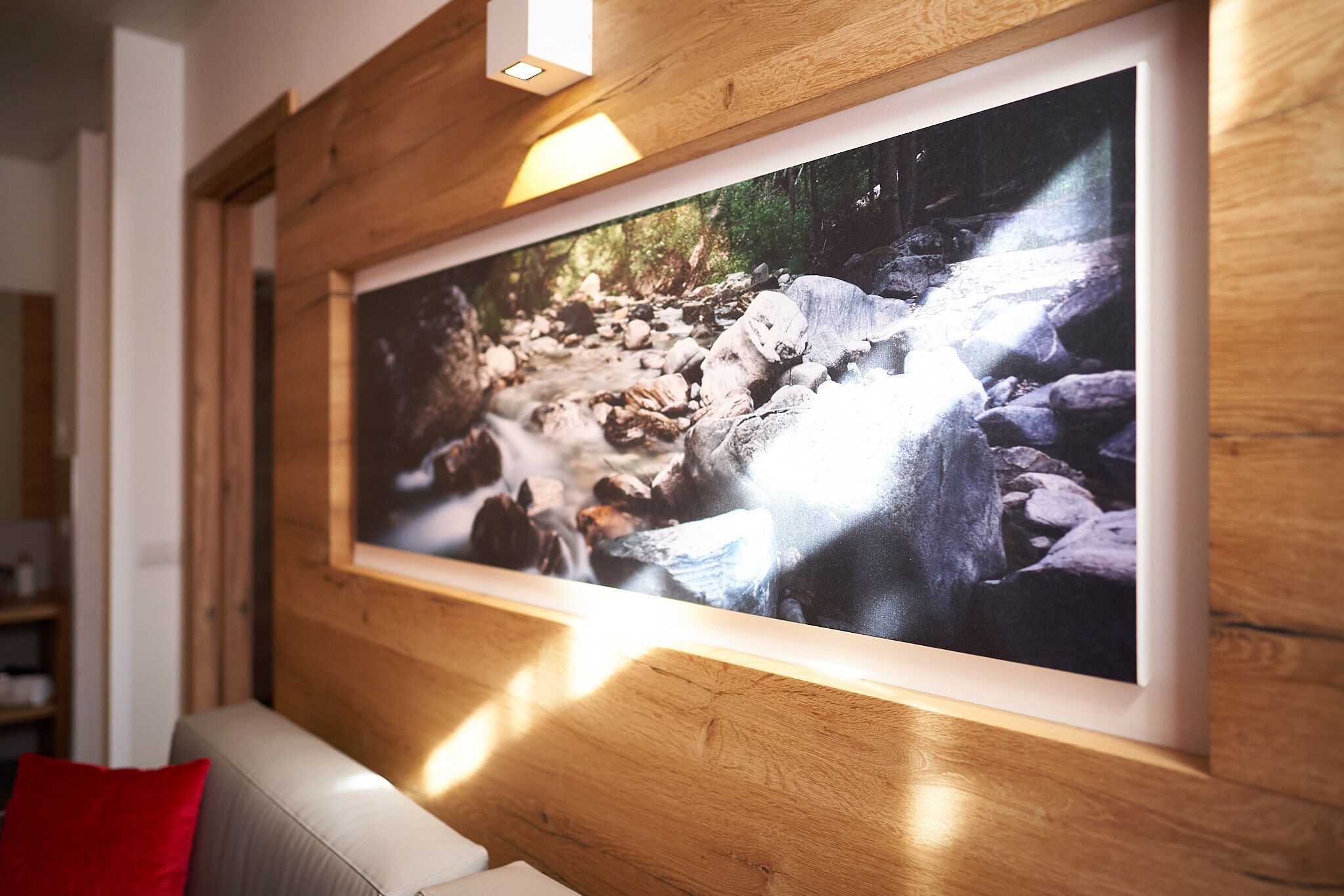 A framed photograph of a rocky stream on a wooden wall.