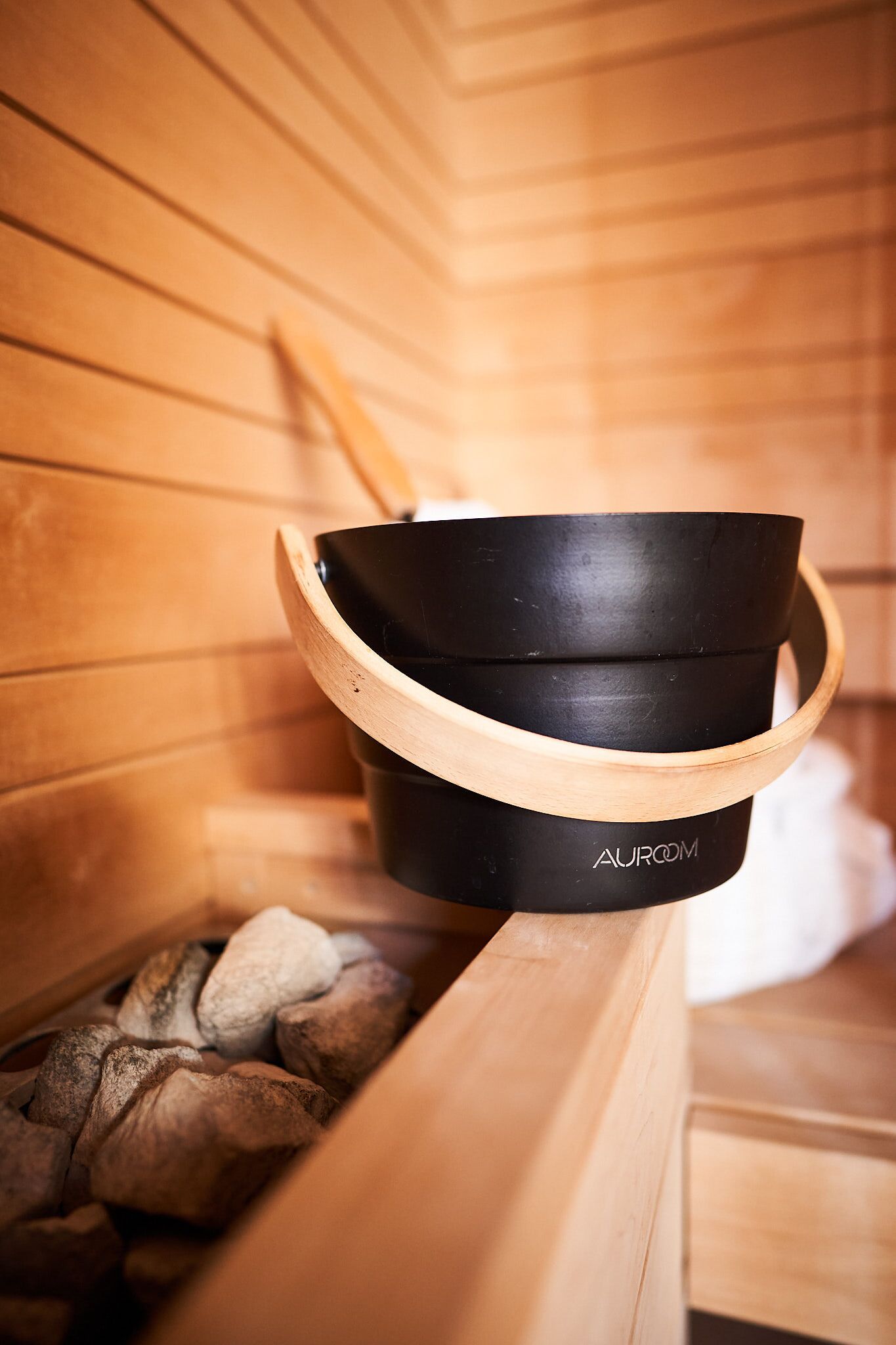 A black and wooden sauna bench with a built-in heater, surrounded by logs.