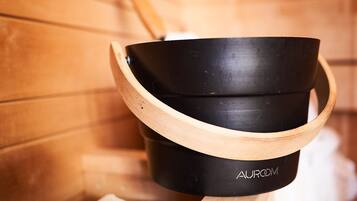 A black and wooden sauna bench with a built-in heater, surrounded by logs.