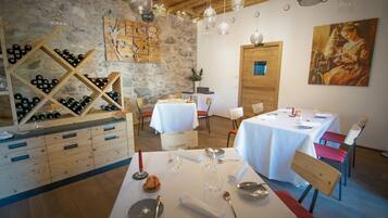 A restaurant with wooden tables and chairs, a wine rack, and a painting on the wall.