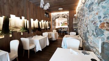 A restaurant with wooden walls, stone accents, and white tables and chairs.