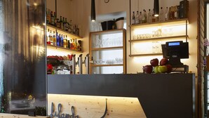 A modern bar area with wooden ceiling beams, a counter with a name sign, shelves with bottles, and a digital display. - La Filanda Relax & Gourmet (Denno)