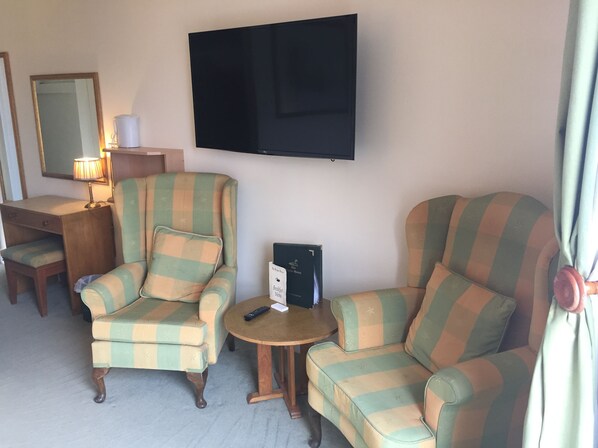 A living room with two armchairs, a small table, a lamp, a television, and a coffee maker. - Faythe Guesthouse (Wexford)