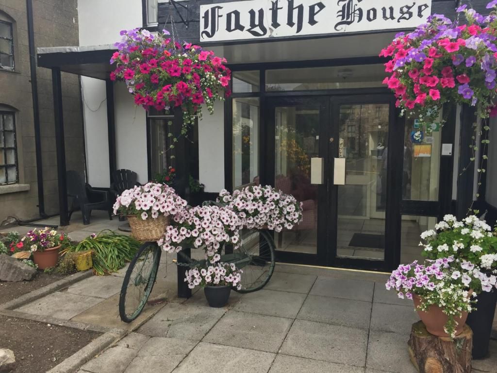 A storefront with a sign reading 'Faythe House.' There are potted plants and a bicycle outside.