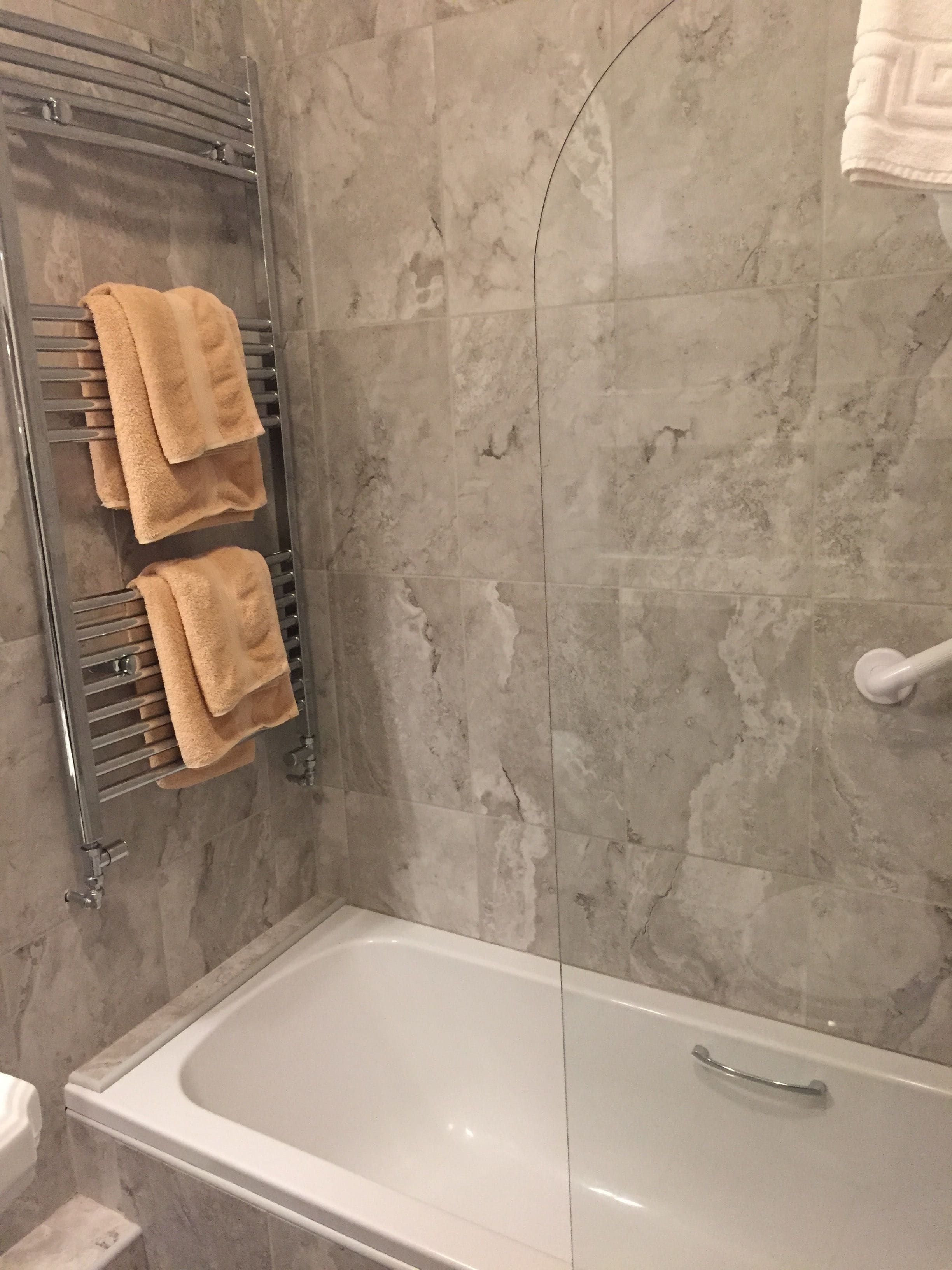 A bathroom with a bathtub, a towel rack with two towels, and a shower area.