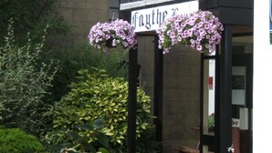A building entrance with hanging flower baskets and a sign above. - Faythe Guesthouse (Wexford)