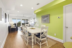 A dining area with a white table and chairs, a green accent wall, and a view to the outside. - OCEANFRONT Midisle Prvt Pool 3New Baths,Kitchen,Floors, AC,Total Renovation!     (Fripp Island)